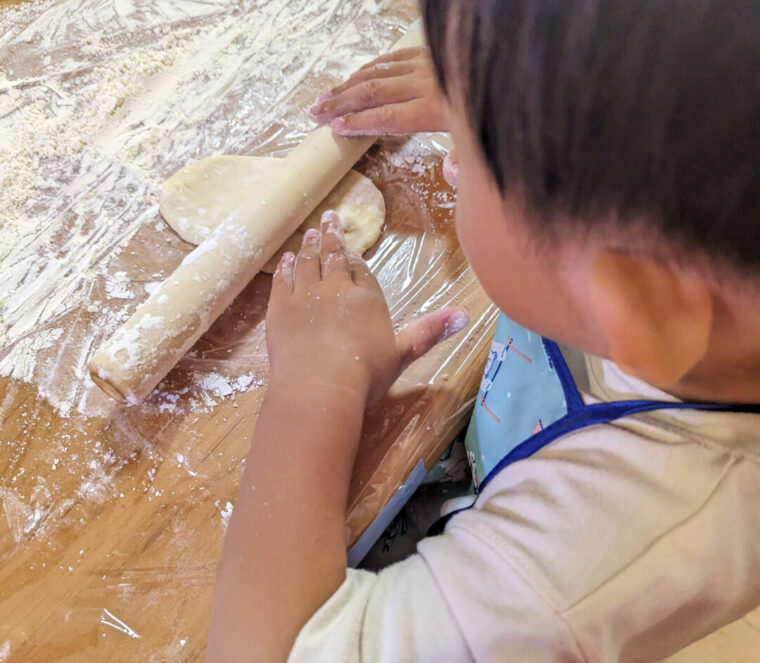 子供がピザ生地を伸ばす