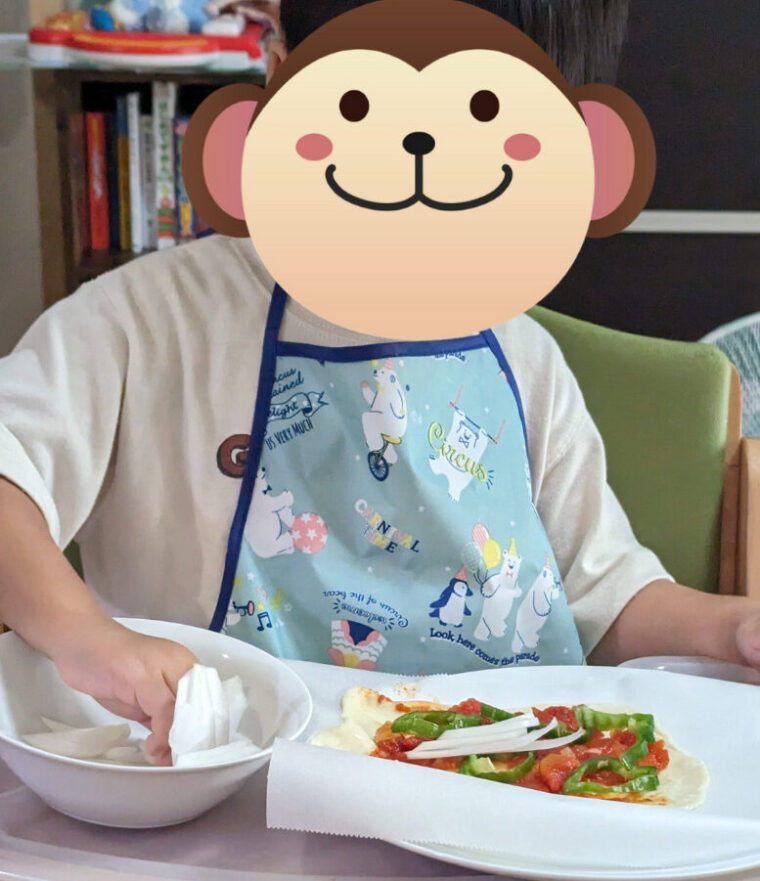 子供がピザ具材をのせる